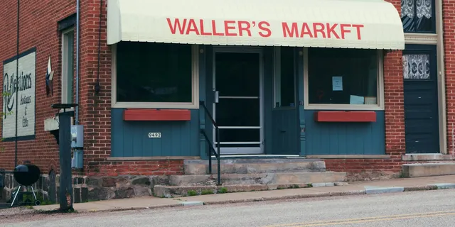 A small brick corner market with a cream awning on a quiet street